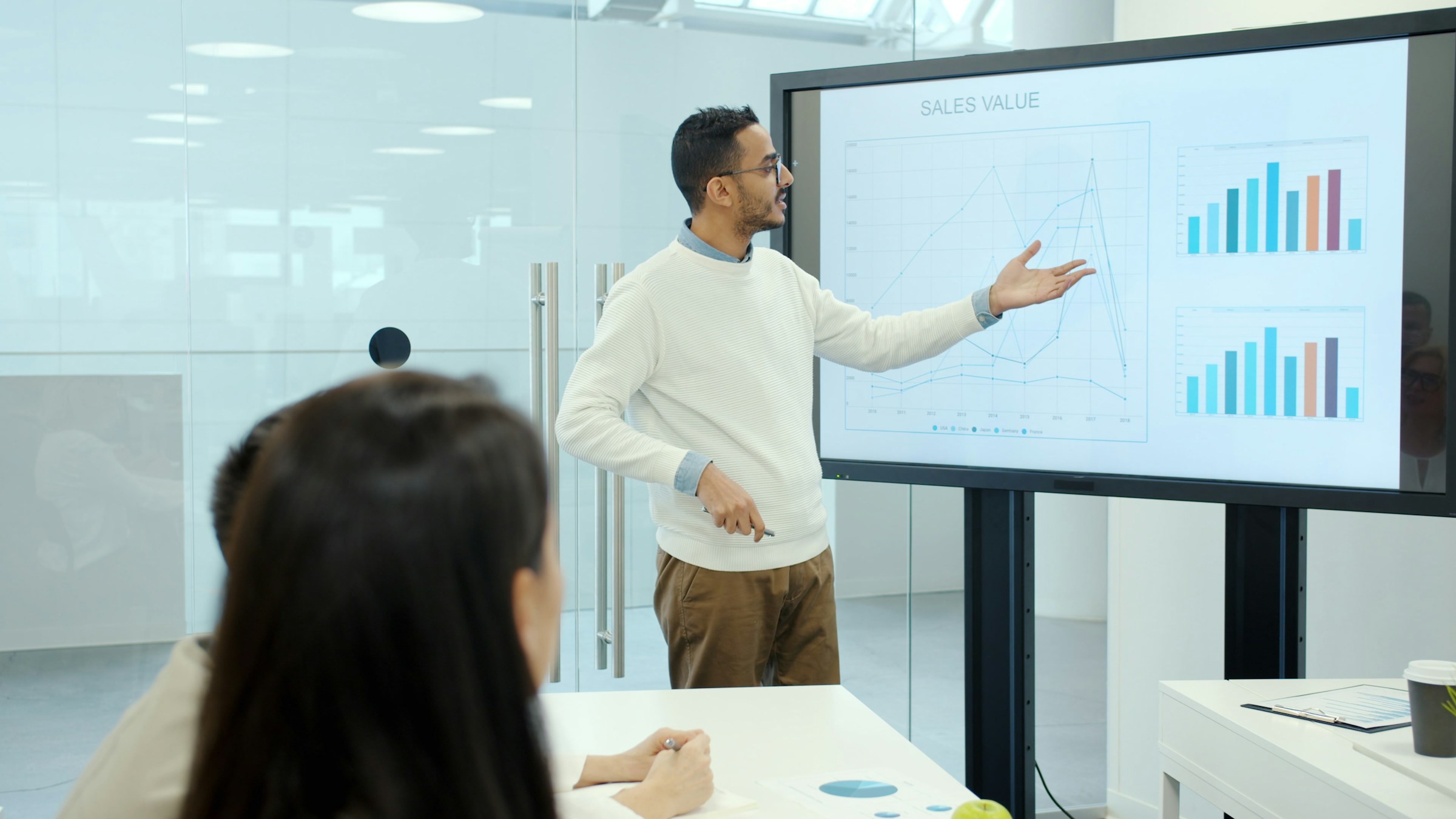 Team analyzing quarterly sales performance data displayed on a screen during a business meeting